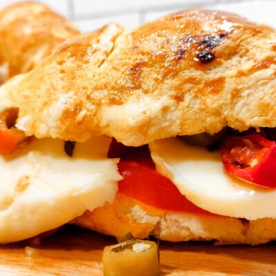 a sliced baguette filled with mozzarella, tomatoes and peppers