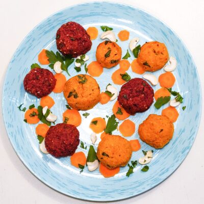 A top down view of a plate that contains a power balls recipe, surrounded by carrot slices, cashew, and parsley